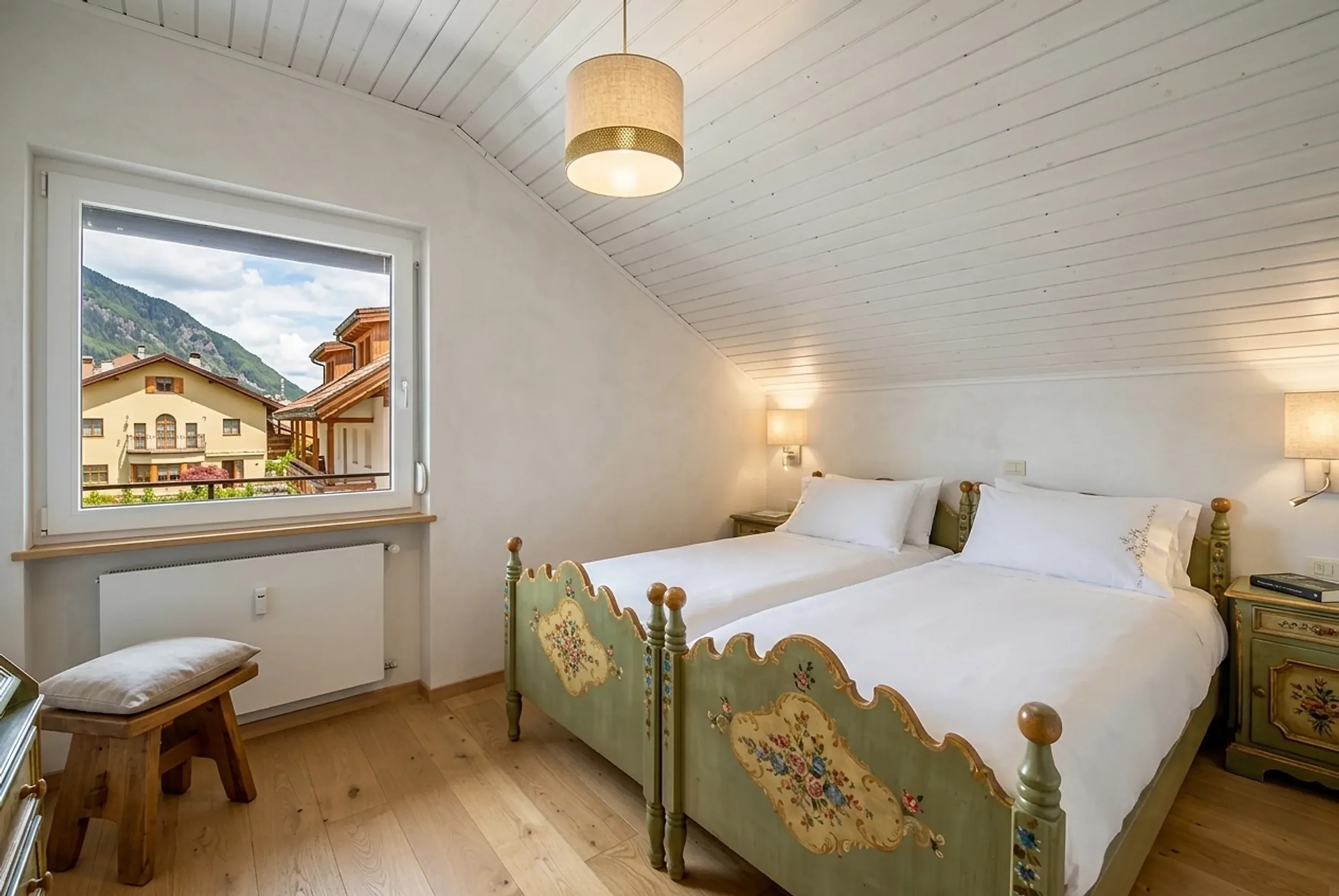 Camera da letto con letti dipinti a mano e finestra sulle montagne, in un appartamento a Brunico